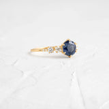 This engagement ring features 925 sterling silver with yellow gold plating, set with a deep blue round cut blue stone, exuding classic and noble elegance