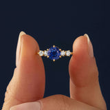 This engagement ring features 925 sterling silver with yellow gold plating, set with a deep blue round cut blue stone, exuding classic and noble elegance